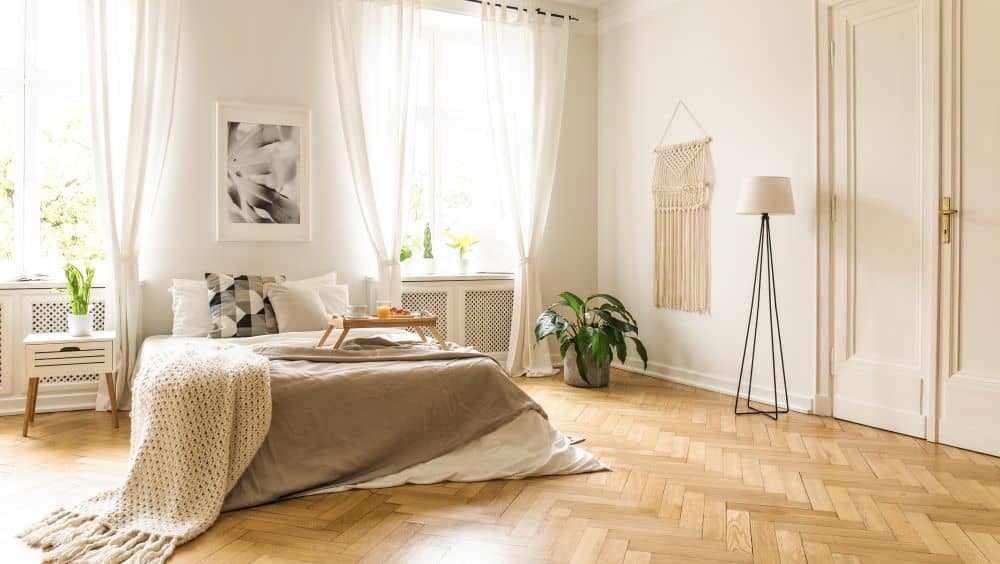 A cozy bedroom with wooden flooring in herringbone pattern.