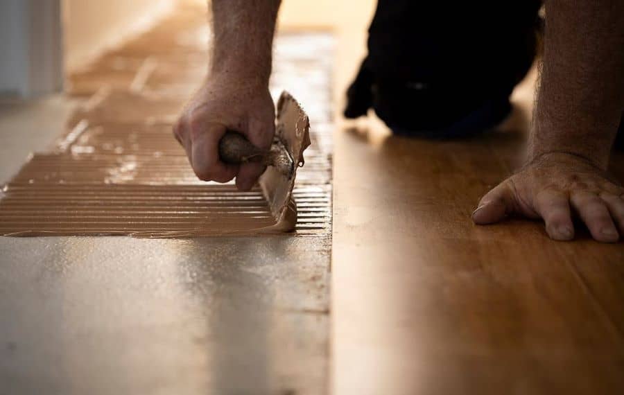 Hard set adhesives are applied along the subfloor to hold the flooring material in place firmly.