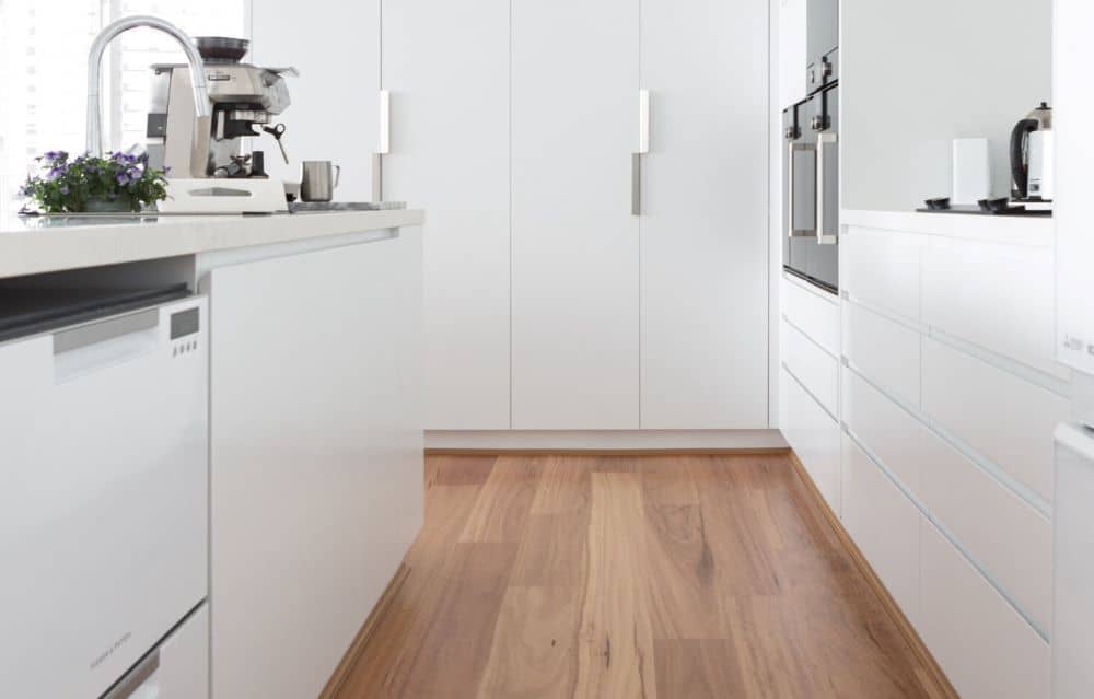 Modern white kitchen with acclimatised timber flooring.