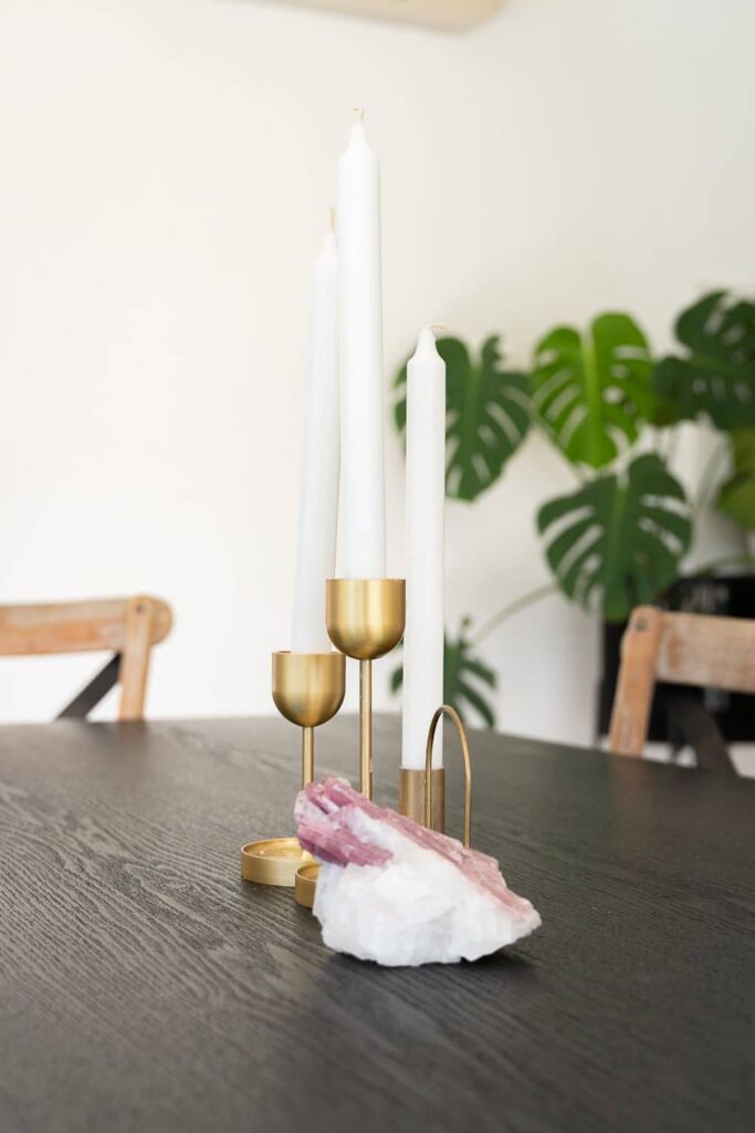 Candles on the dining table with Monstera plant seen on the background.