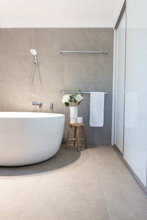 Grey bathroom wall, white bathtub.