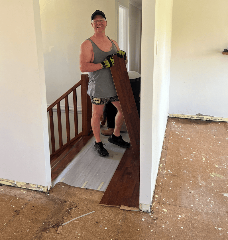 Levi from Online Flooring Store smiling while removing old laminate flooring during the Moore River renovation project.