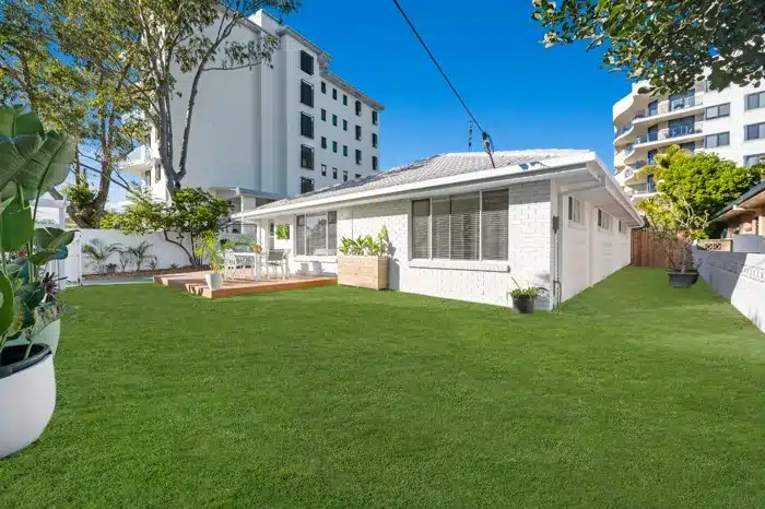 Backyard renovation of Tweed Heads duplex with artificial turf, timber deck and white exterior