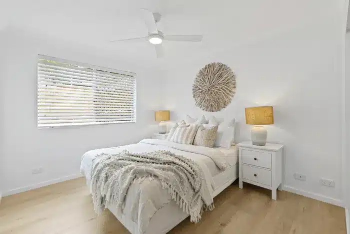 Renovated master bedroom with hybrid flooring, white interiors and natural decor accents